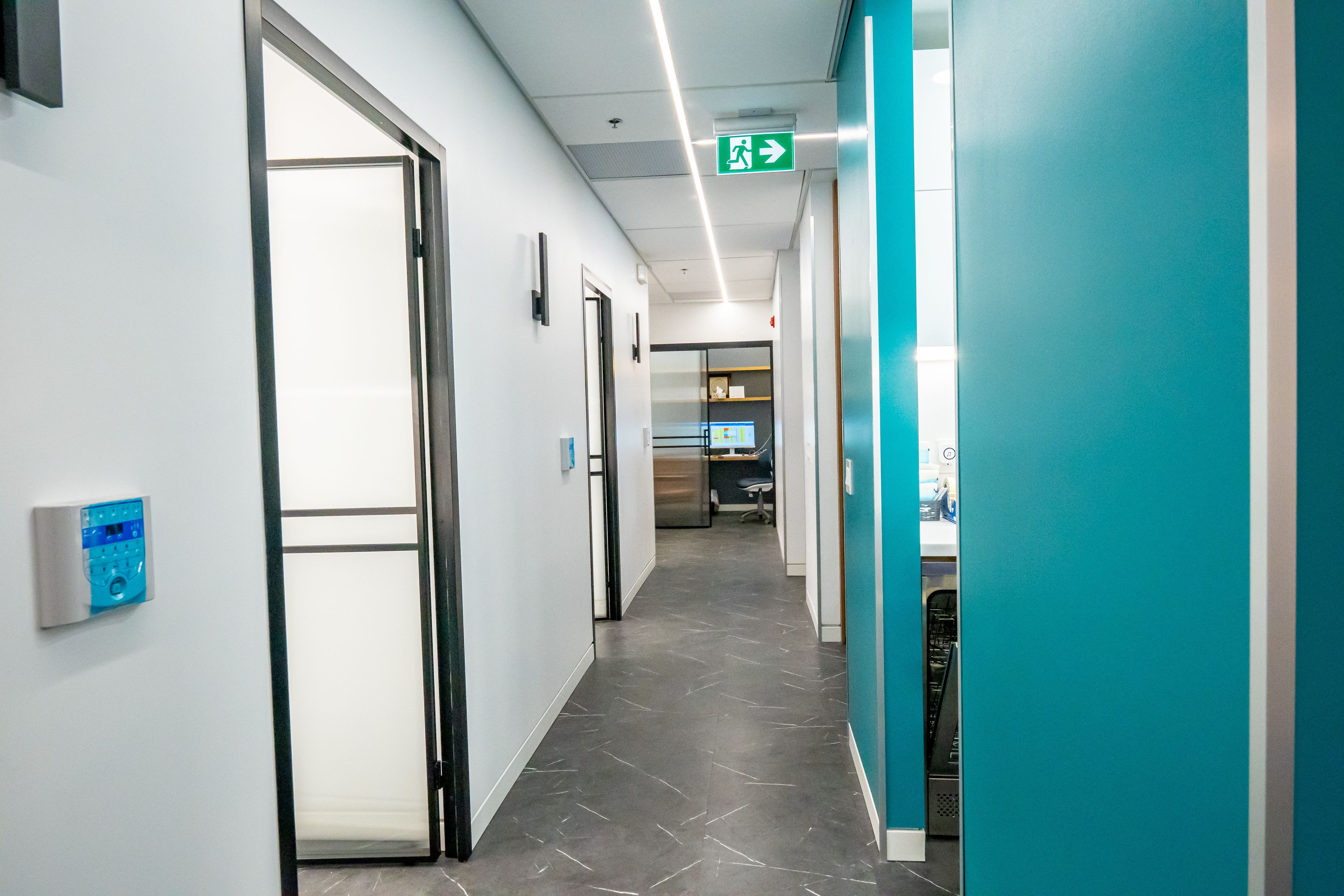 Accessible hallway with illuminated exit signage inside the Dentix24 clinic